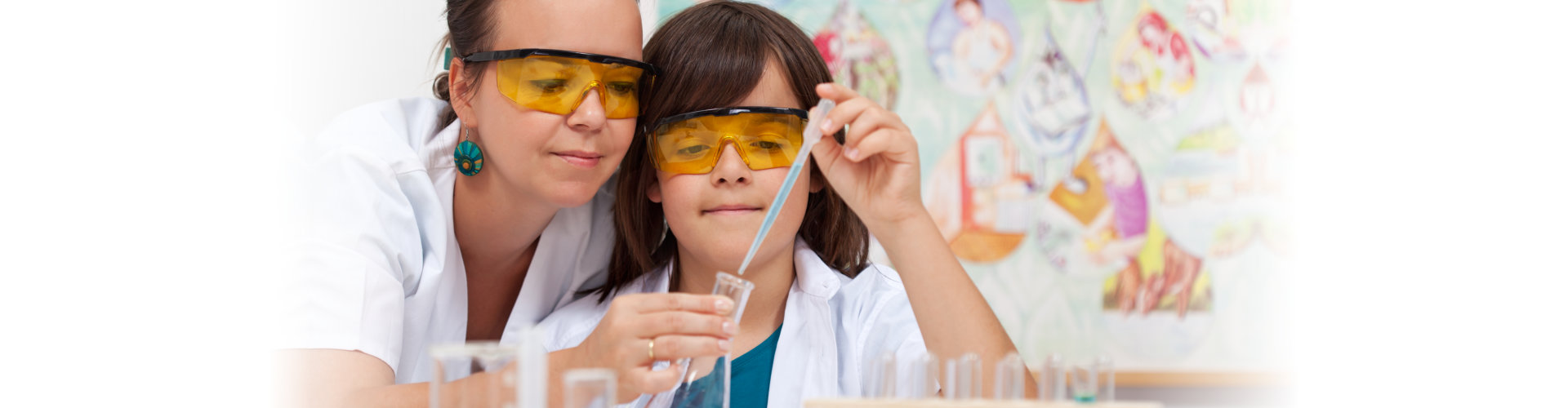 little girl on chemistry class guided by her teacher